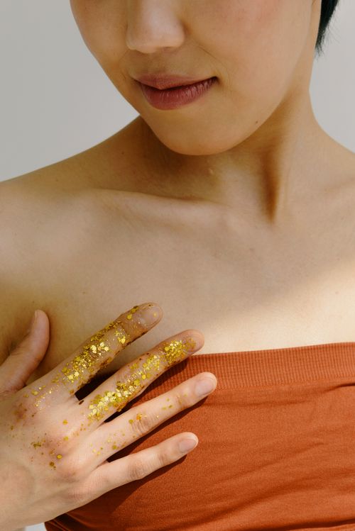 Free Close-up portrait of a young woman with golden glitter on her fingers, highlighting beauty and elegance. Stock Photo