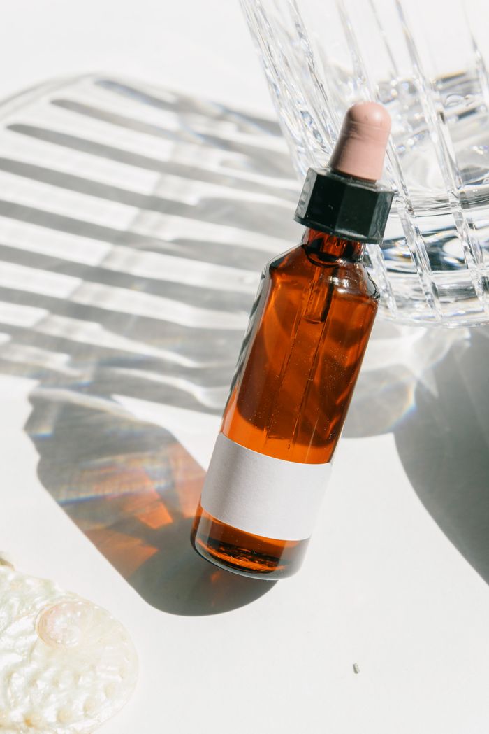Amber glass dropper bottle with a blank label in daylight — photo by Ksenia Chernaya on Pexels