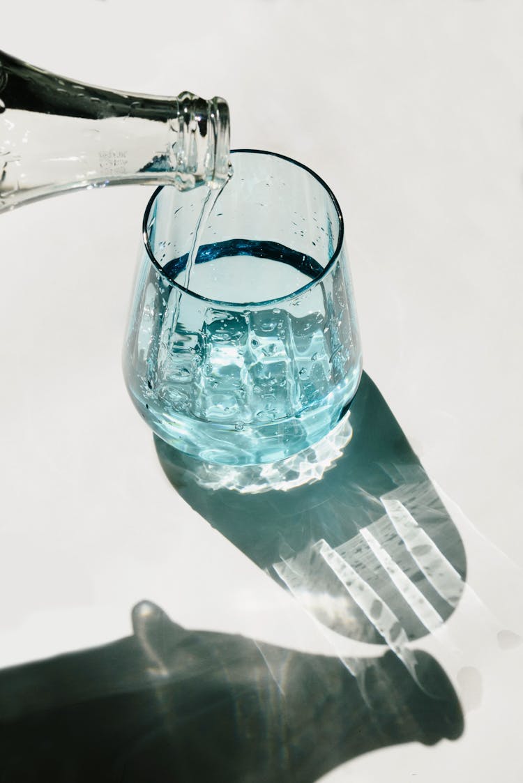 Person Pouring Water On Clear Drinking Glass