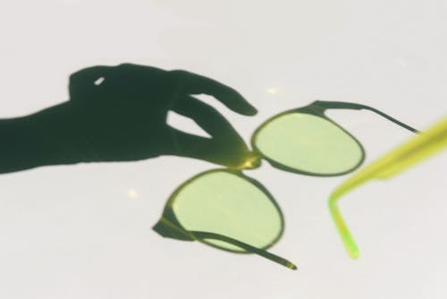 Shadow of A Person's Hand Holding Green Framed Eyeglasses