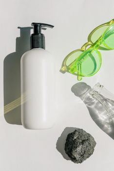 A modern arrangement featuring a pump bottle, green sunglasses, and a glass bottle.