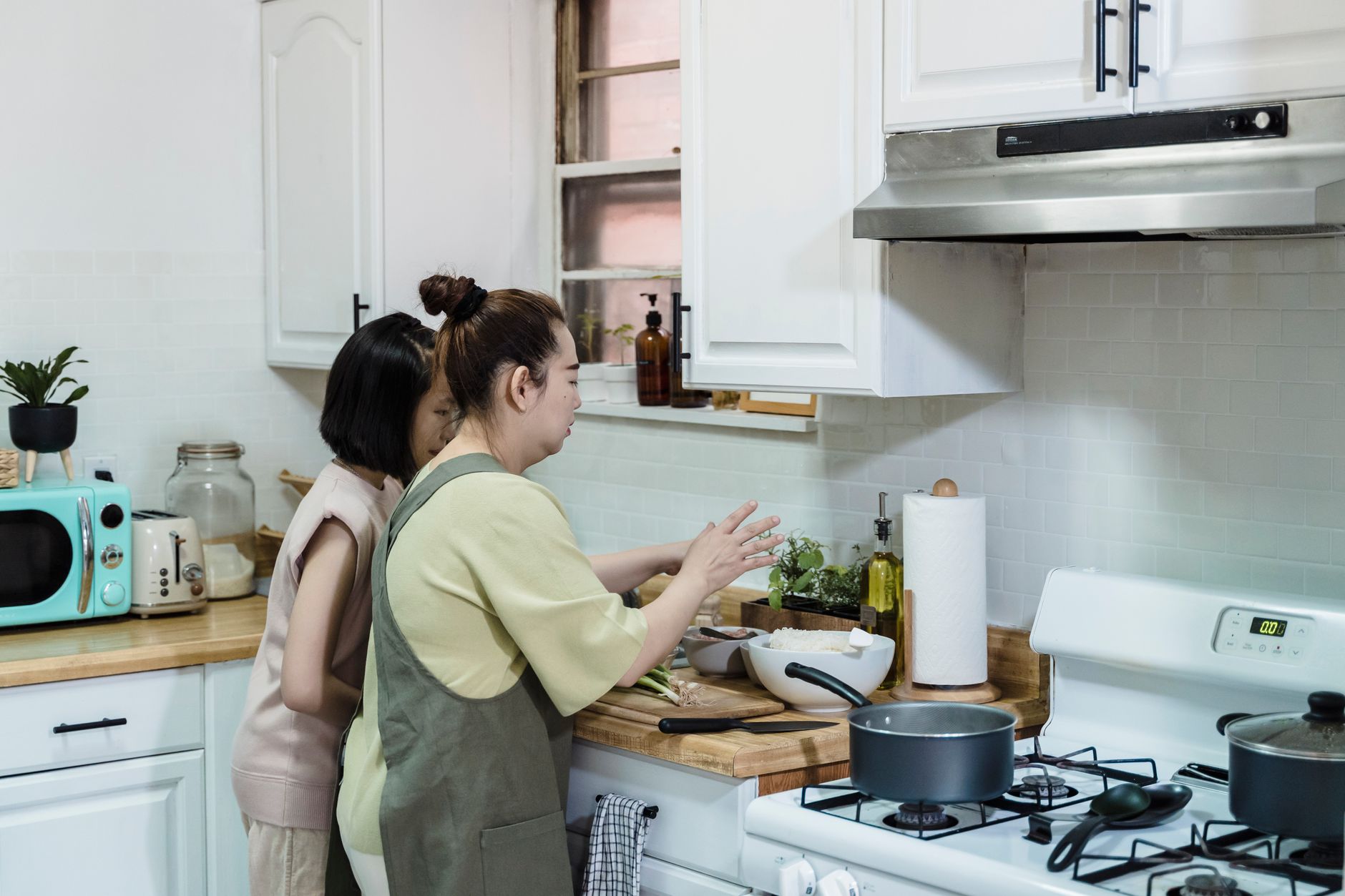 Asian mother and daughter preparing a meal in a modern home kitchen.