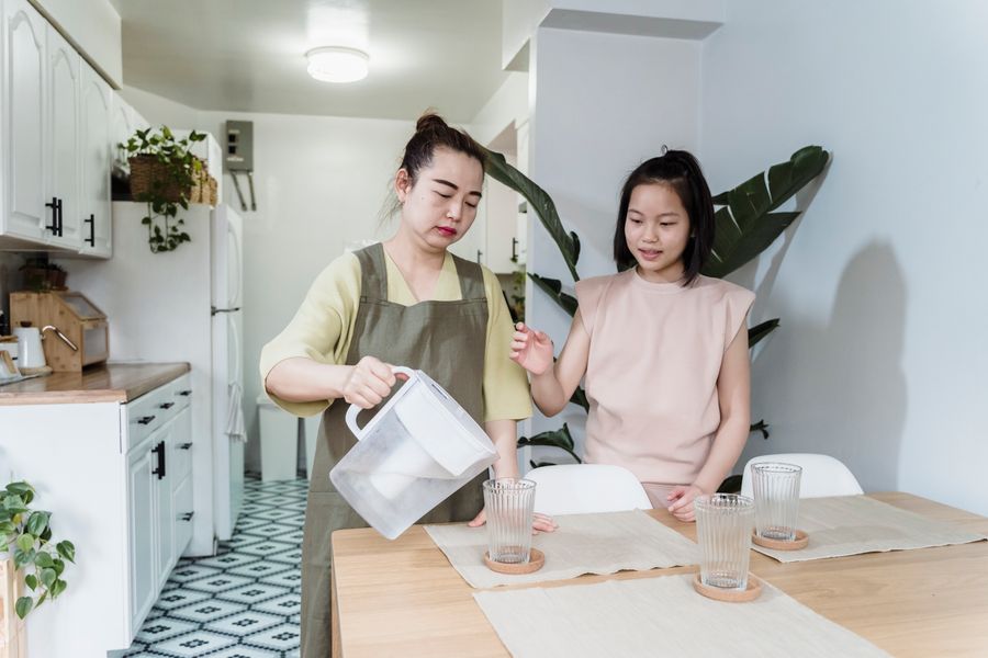 Parent and child pouring filtered water at the kitchen table
