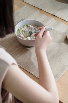 A person enjoys a bowl of soup at a table, captured from above.