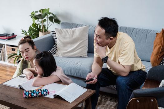 A family spends quality time studying together in a comfortable living room setting.