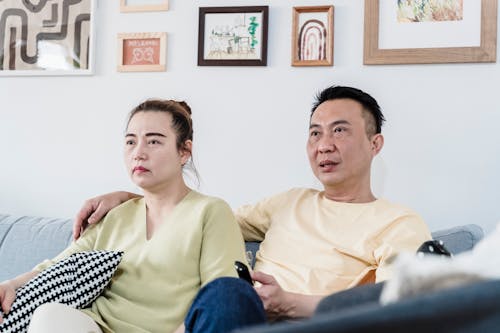 A Couple Sitting on the Couch while Watching TV