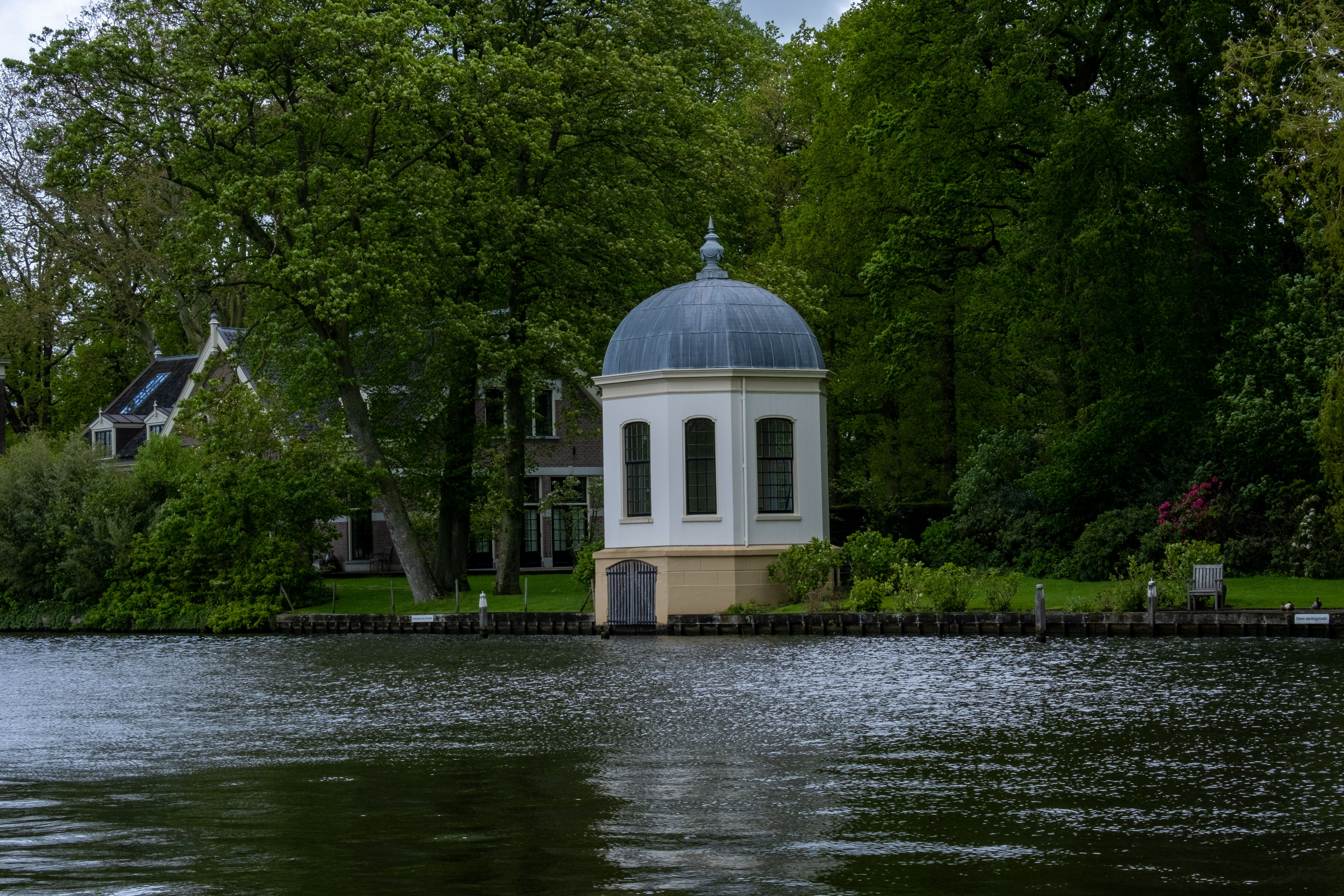 Tranquil chapel surrounded by lush greenery beside a river in Loenen aan de Vecht.