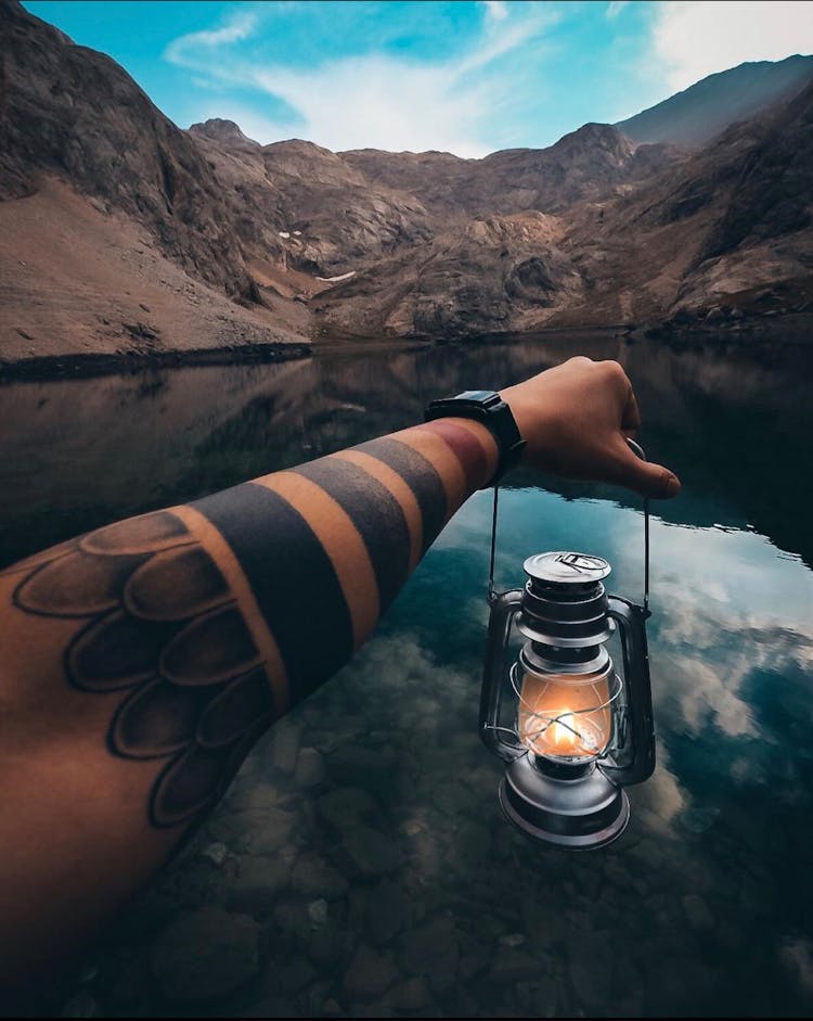 Arm Holding Lantern Over Lake