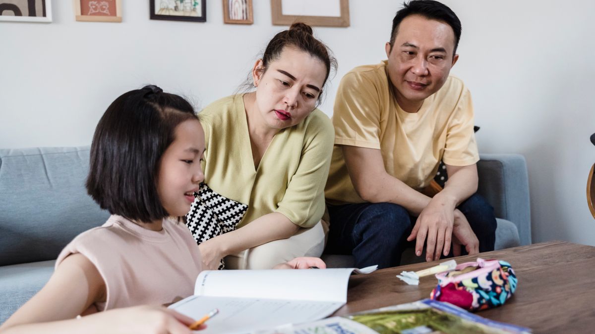 Parents assisting daughter with her homework in a cozy living room setting.