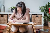 A Girl Doing her Homework on a Bed Tray