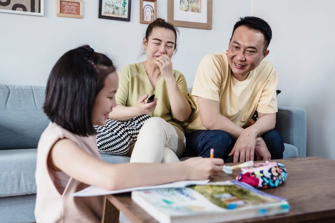 Older child sharing completed schoolwork with supportive parents at home