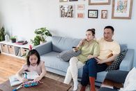 A Girl Doing her Homework beside her Parents in a Living Room