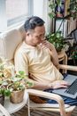 A Man Using a Laptop while Sitting in an Armchair