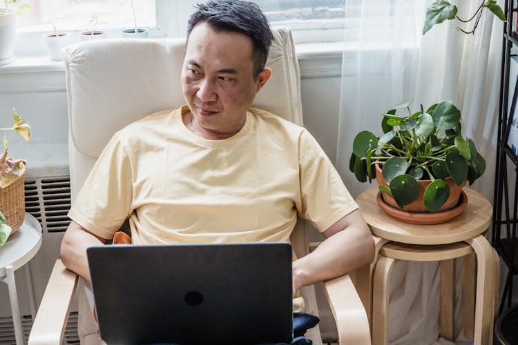 A Man Using A Laptop While Sitting On A Lounge Chair