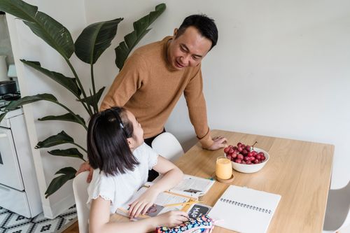 Free A father assists his daughter with homework at the kitchen table. Stock Photo
