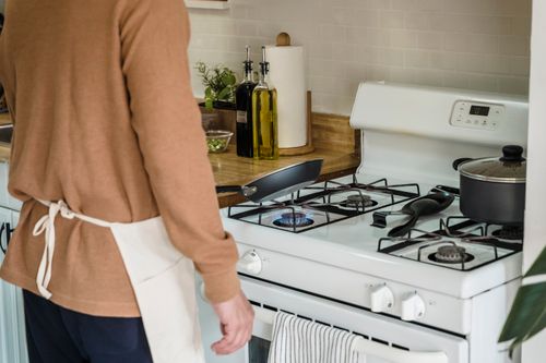 Free A person preparing food on a gas stove in a cozy kitchen setting. Stock Photo