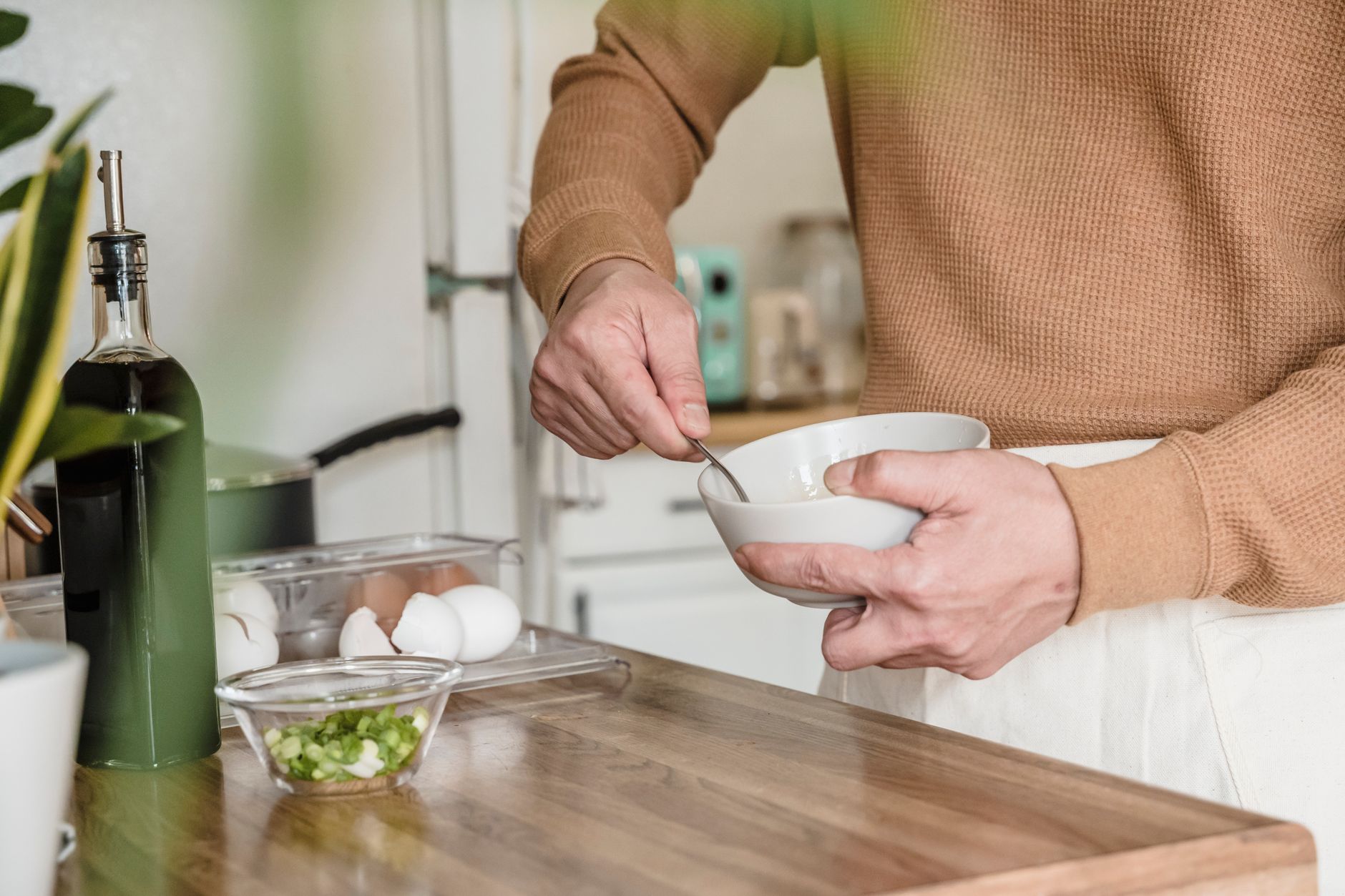 person taking a spoonful of olive oil in the kitchen