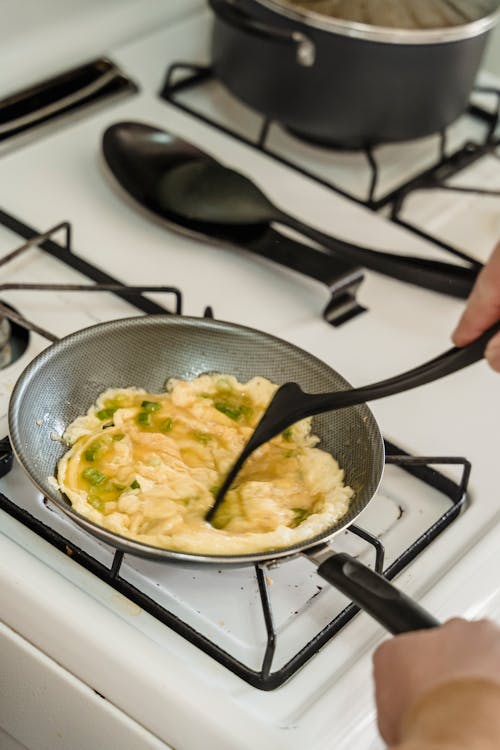 Free A Person Cooking Scrambled Eggs in a Pan Stock Photo
