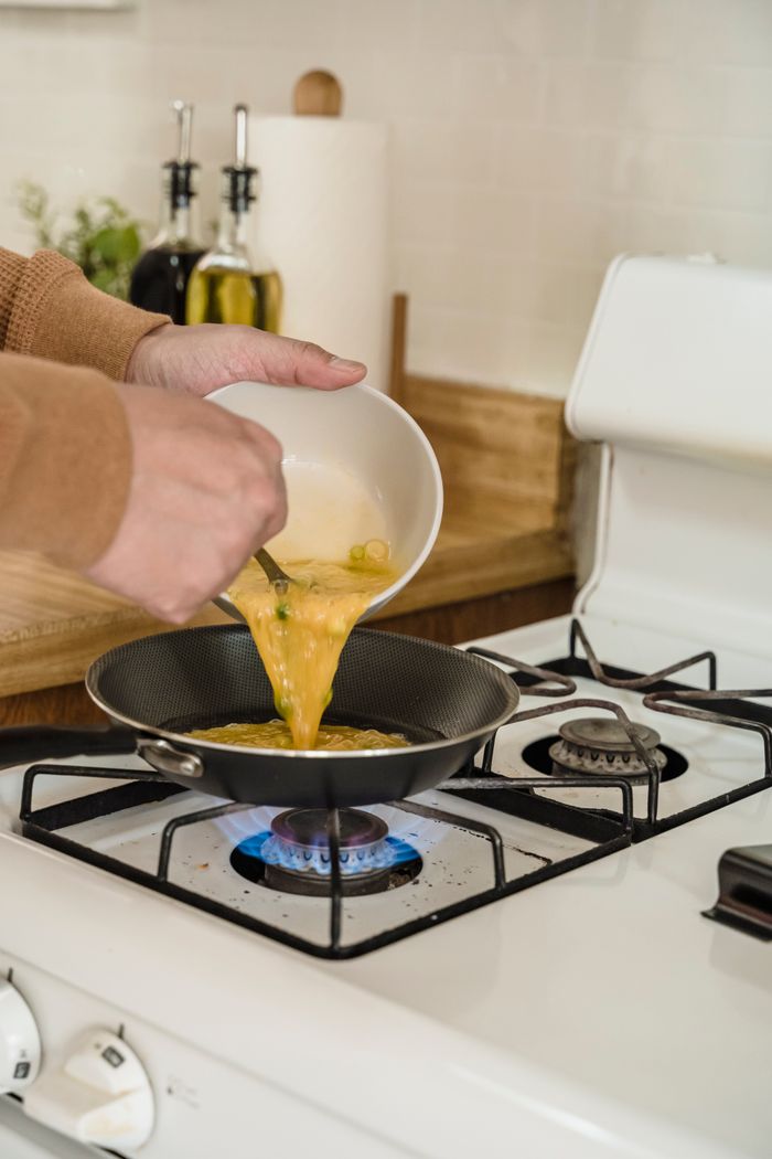 Olive oil being poured into a hot pan on a gas burner — photo by Annushka Ahuja on Pexels