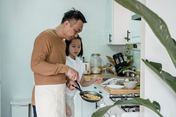 A Man Teaching His Daughter How To Cook Scrambled Eggs