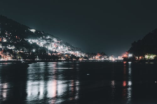 Illuminated Coastal Town on Hills at Night