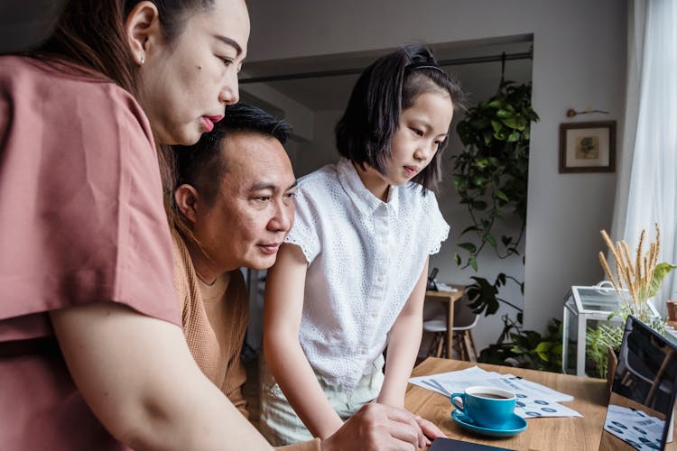 A Family Looking On Computer Monitor On A Table