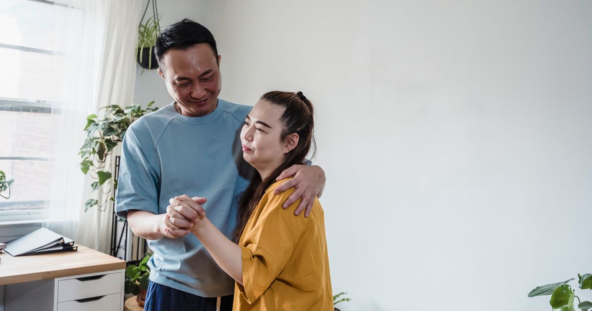 Couple slow dancing together in a bright living room with plants