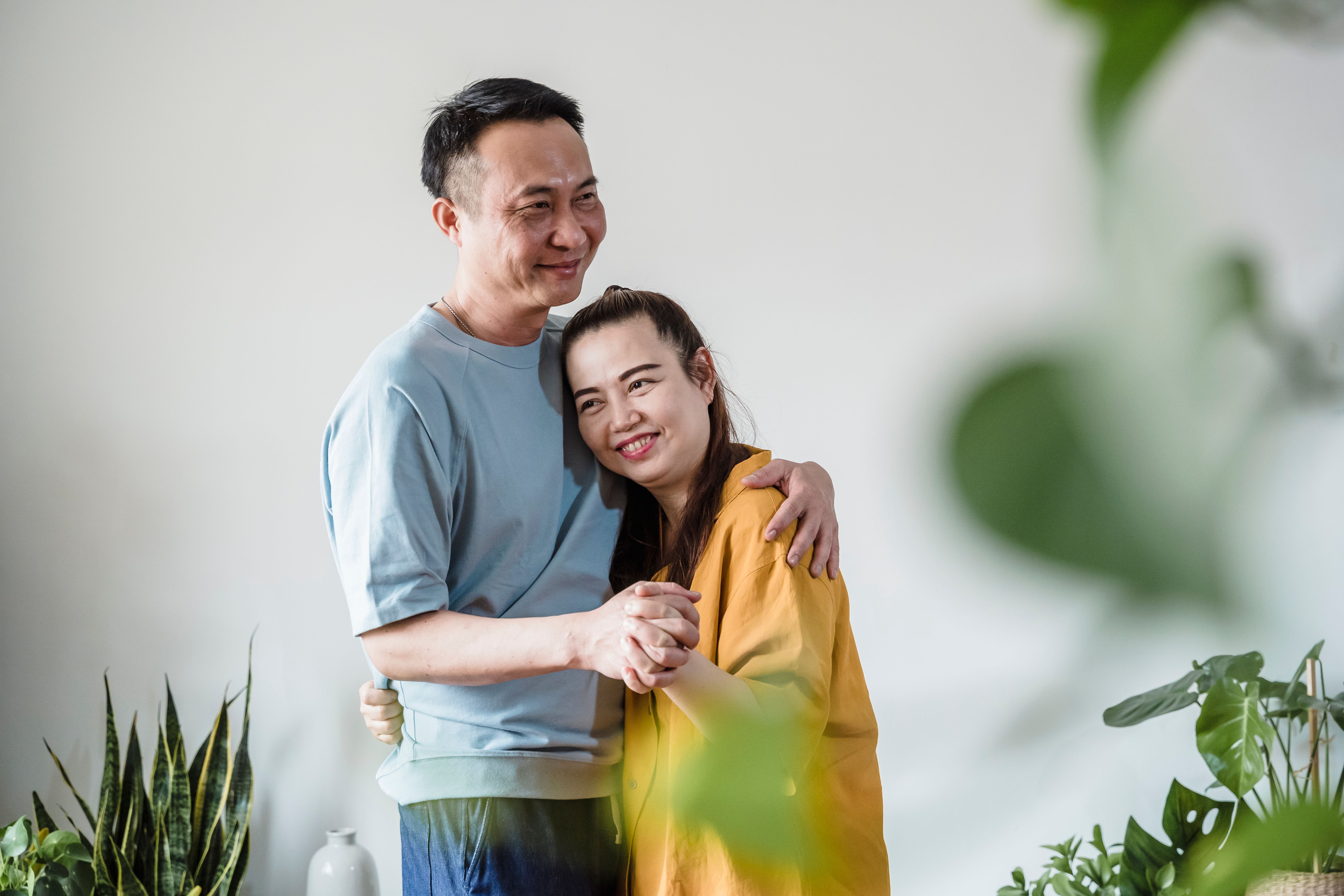 A joyful couple embracing indoors surrounded by lush green plants.