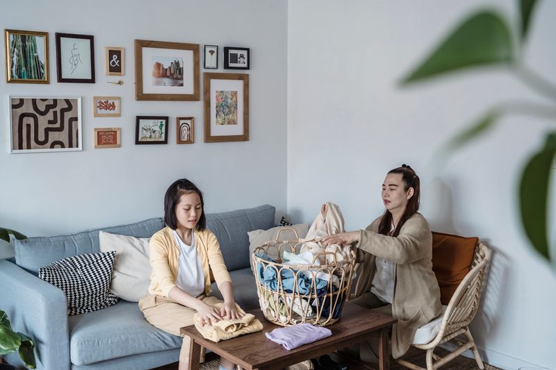 A mother and daughter engaged in folding laundry on a comfortable sofa, enhancing family bonding.