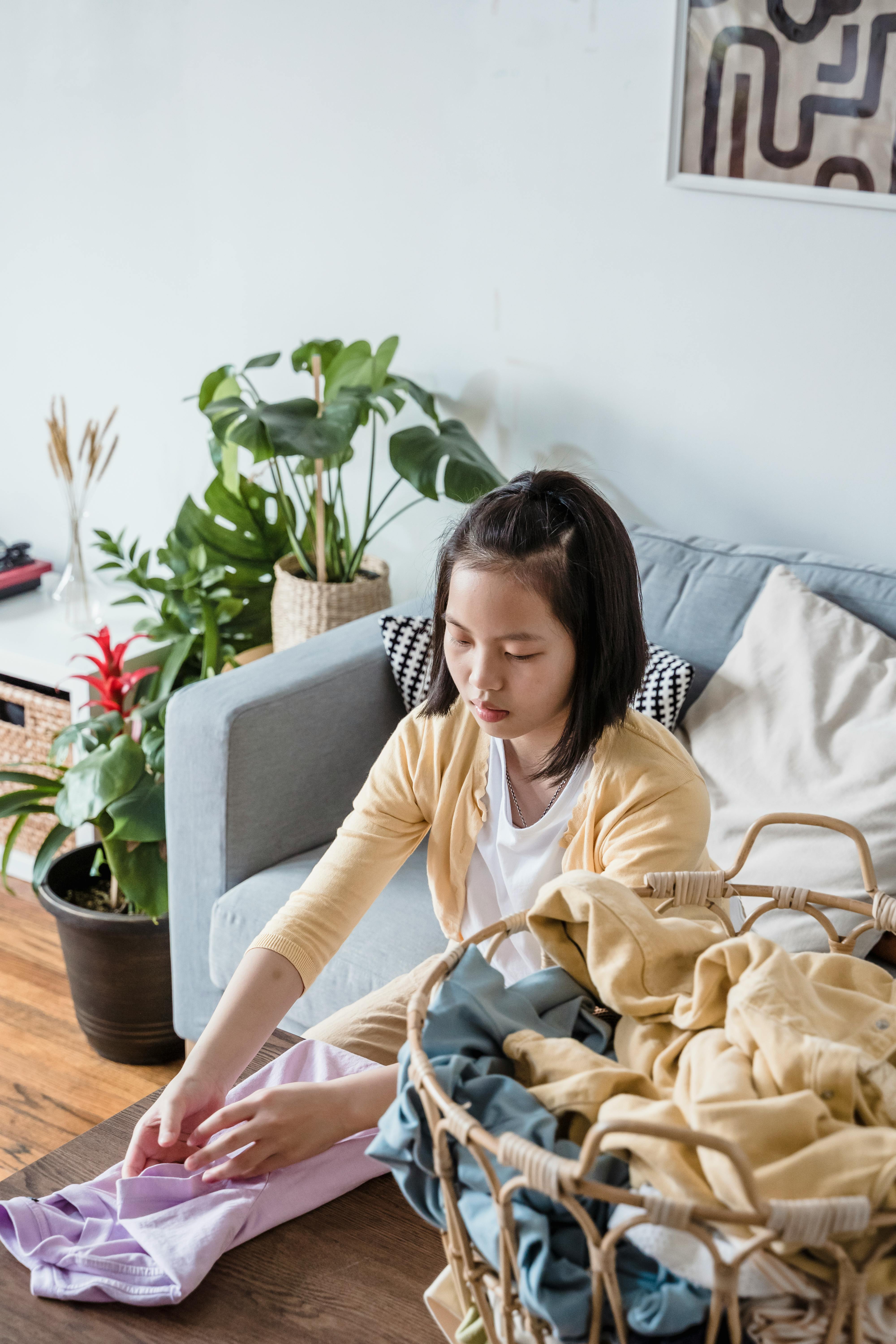 young girl folding clothes on a table