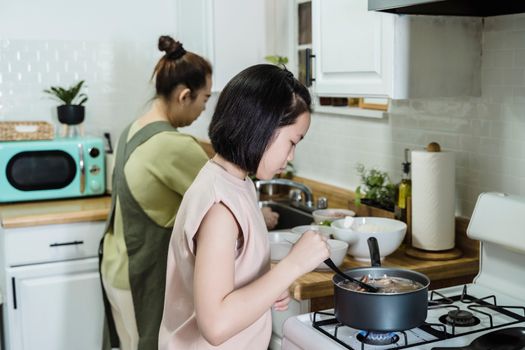 A mother and daughter preparing food together, focusing on family and teamwork in the kitchen.
