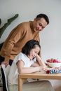 Father looks at his Studying Daughter