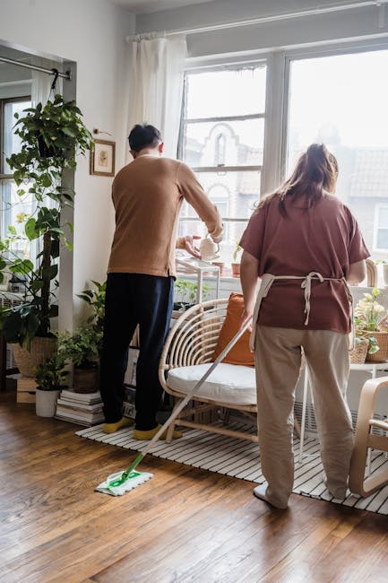 A couple cleaning a living room with indoor plants, showcasing teamwork and home care.