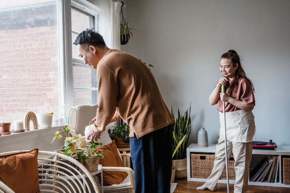 Photo by Annushka Ahuja on Pexels Couple tending to houseplants and cleaning in a cozy, light-filled living room. - Photo by Annushka Ahuja on Pexels