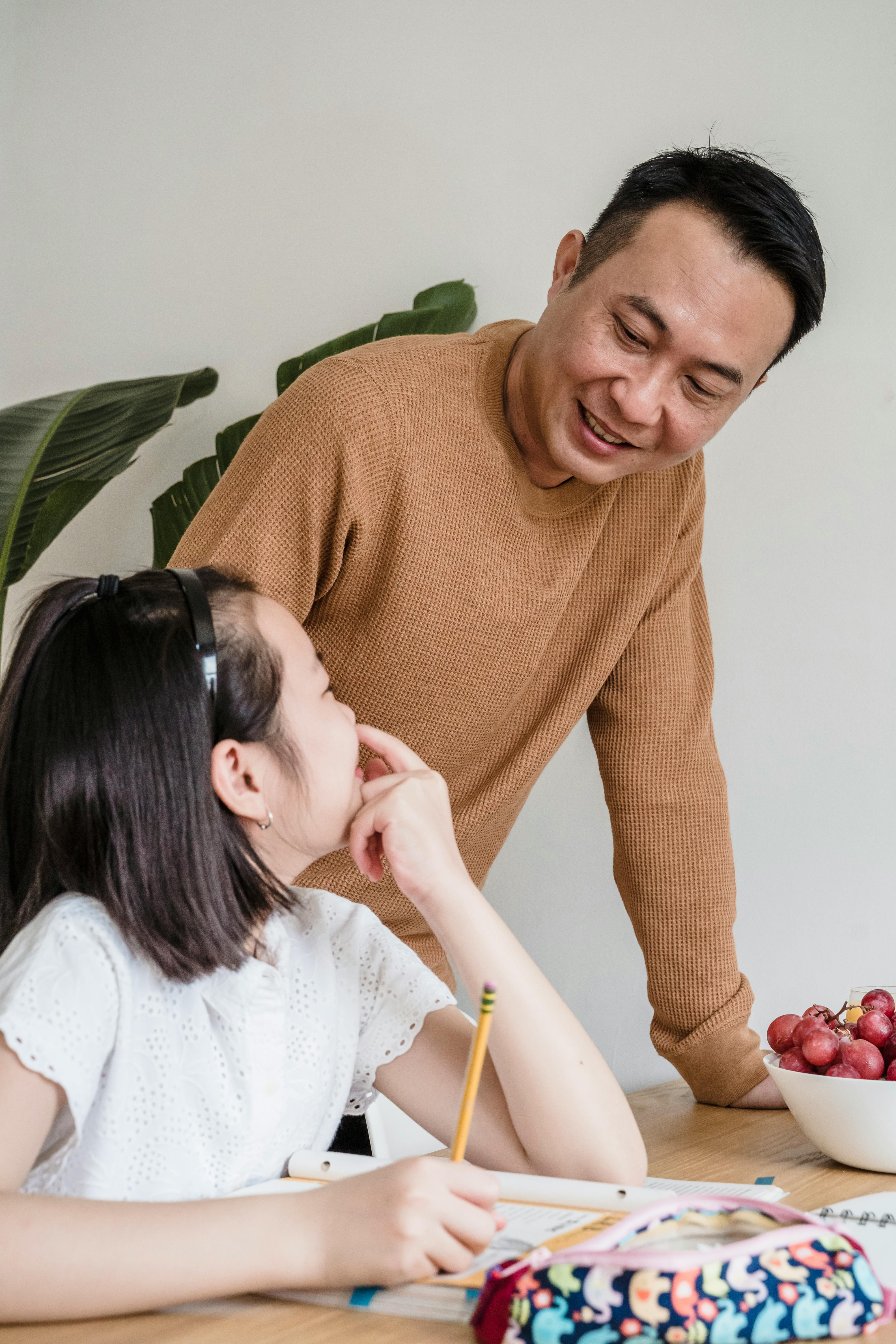 a father standing beside her sitting daughter