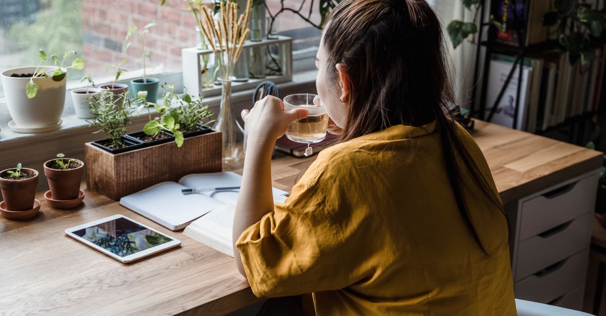 person sitting at a clean desk with a notebook and coffee at 8 AM, sunlight streaming through window