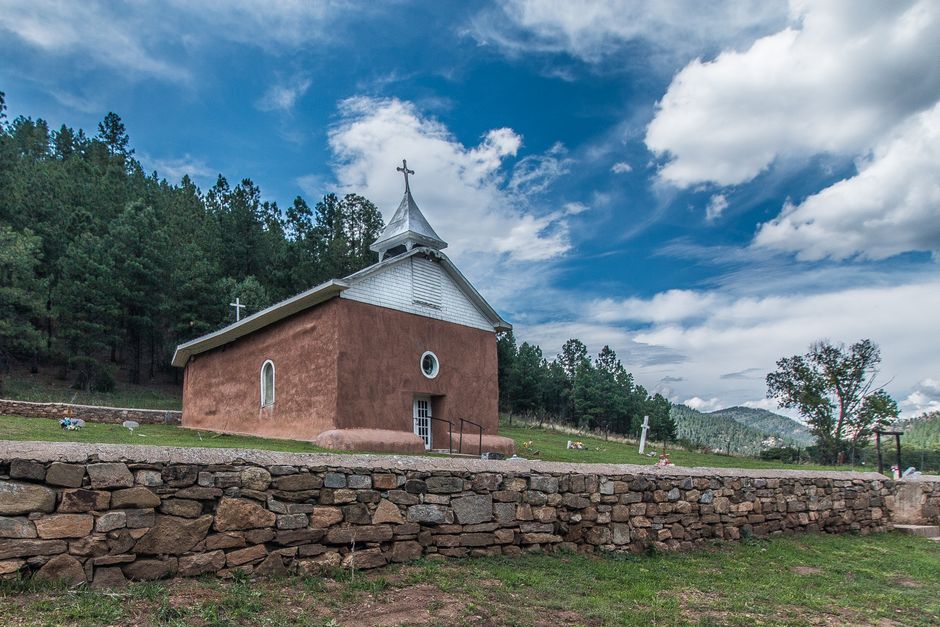 Charming historic church set against lush greenery and vibrant skies in Pecos, NM.