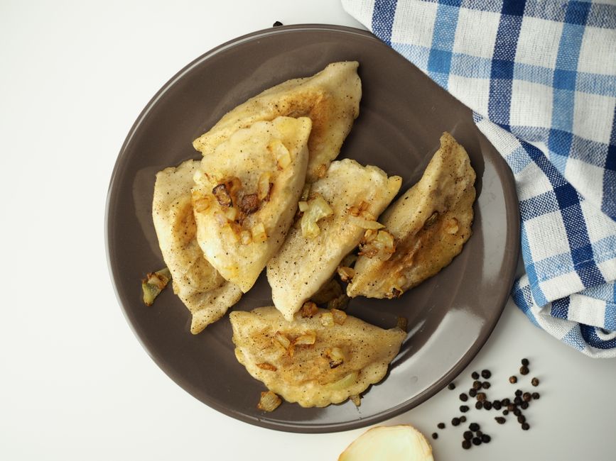 Plate of traditional Polish pierogi with sour cream and herbs in a cozy Warsaw restaurant