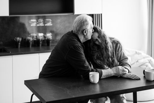 Free Heartfelt black and white portrait of an elderly man comforting a woman at a table. Stock Photo