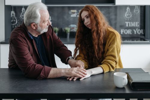 Free Grandfather and granddaughter sharing a comforting moment at the kitchen table, indoors. Stock Photo