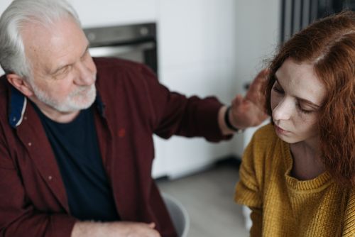 Free Senior man offering comfort to a young woman in a cozy indoor setting. Stock Photo