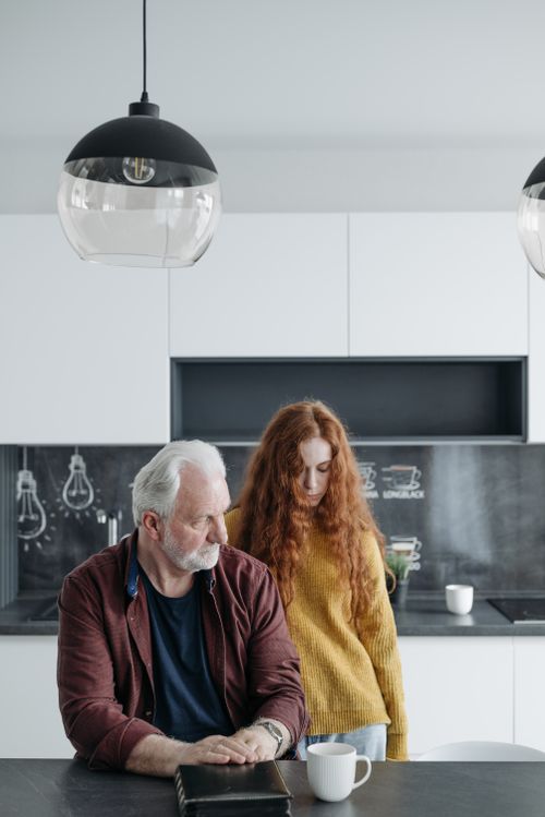 Free An elderly man and his granddaughter share a quiet moment in a modern kitchen. Stock Photo
