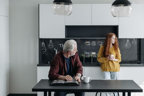 Free An elderly man and a young woman in a kitchen, depicting a family moment. Stock Photo