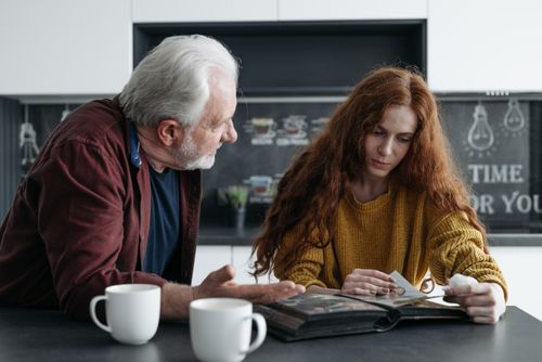 Free Elderly man and young woman looking at a photo album together, evoking emotions and memories. Stock Photo