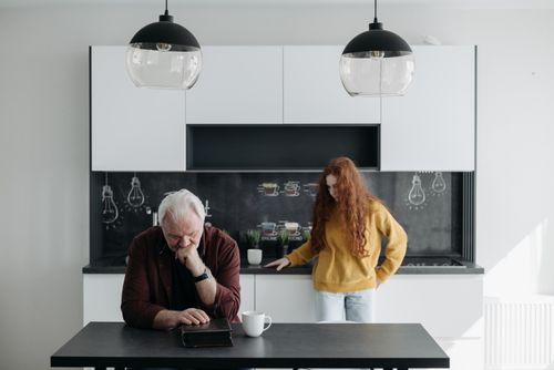 Free An emotional scene of a senior man and a young woman in a modern kitchen, capturing sorrow and family bond. Stock Photo