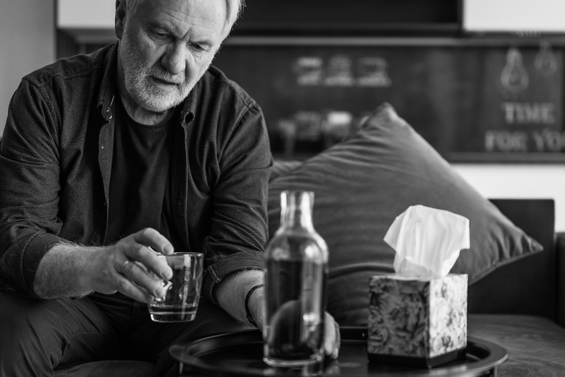 Grayscale Photo of a Man Holding a Glass of Drink