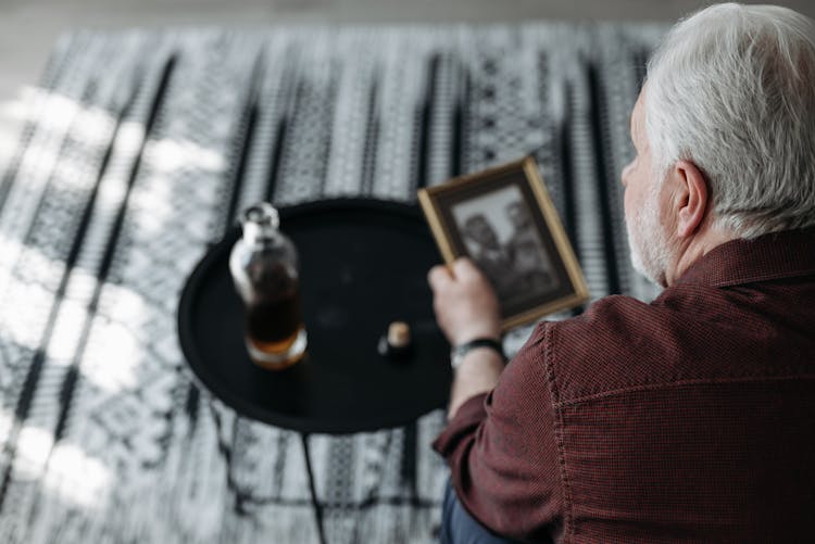 An Elderly Man With Gray Hair Holding A Picture Frame