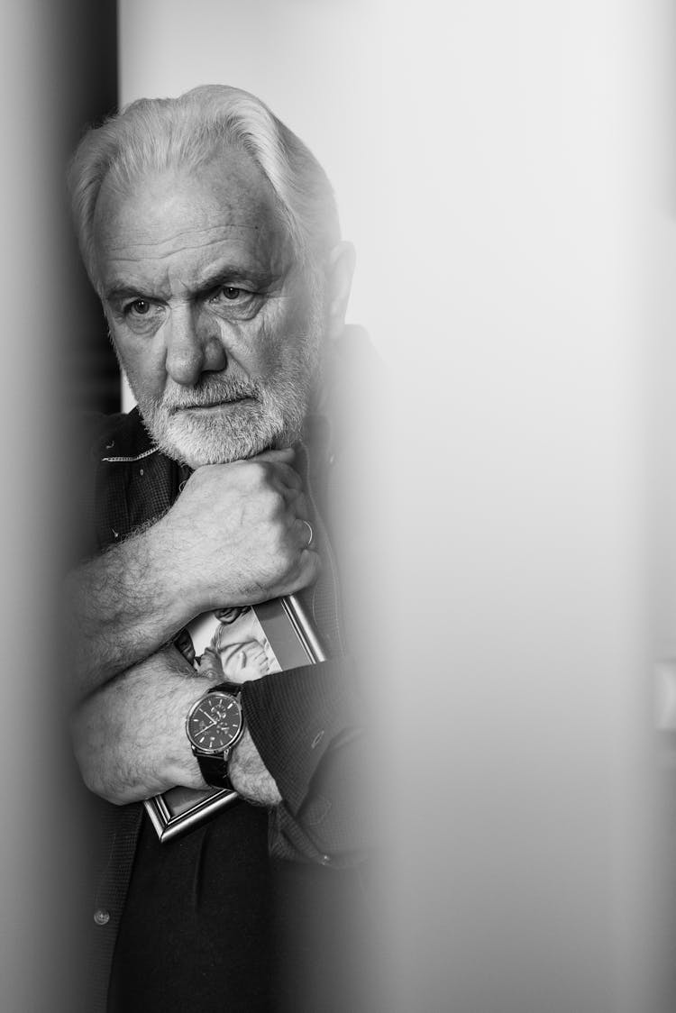 Grayscale Photo Of An Elderly Man Hugging A Picture Frame