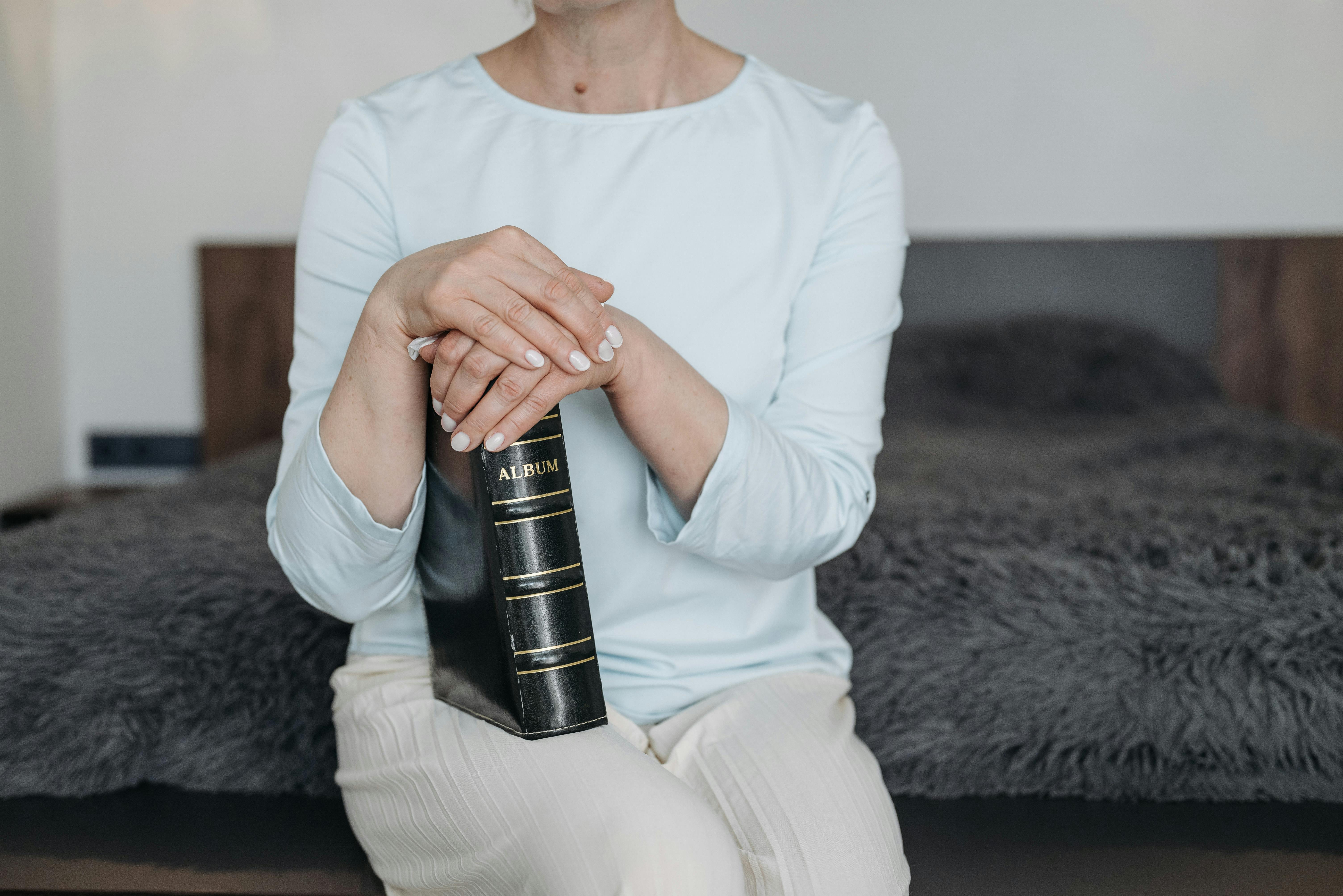 Free A Woman Sitting on Bed Holding a Photo Album Stock Photo