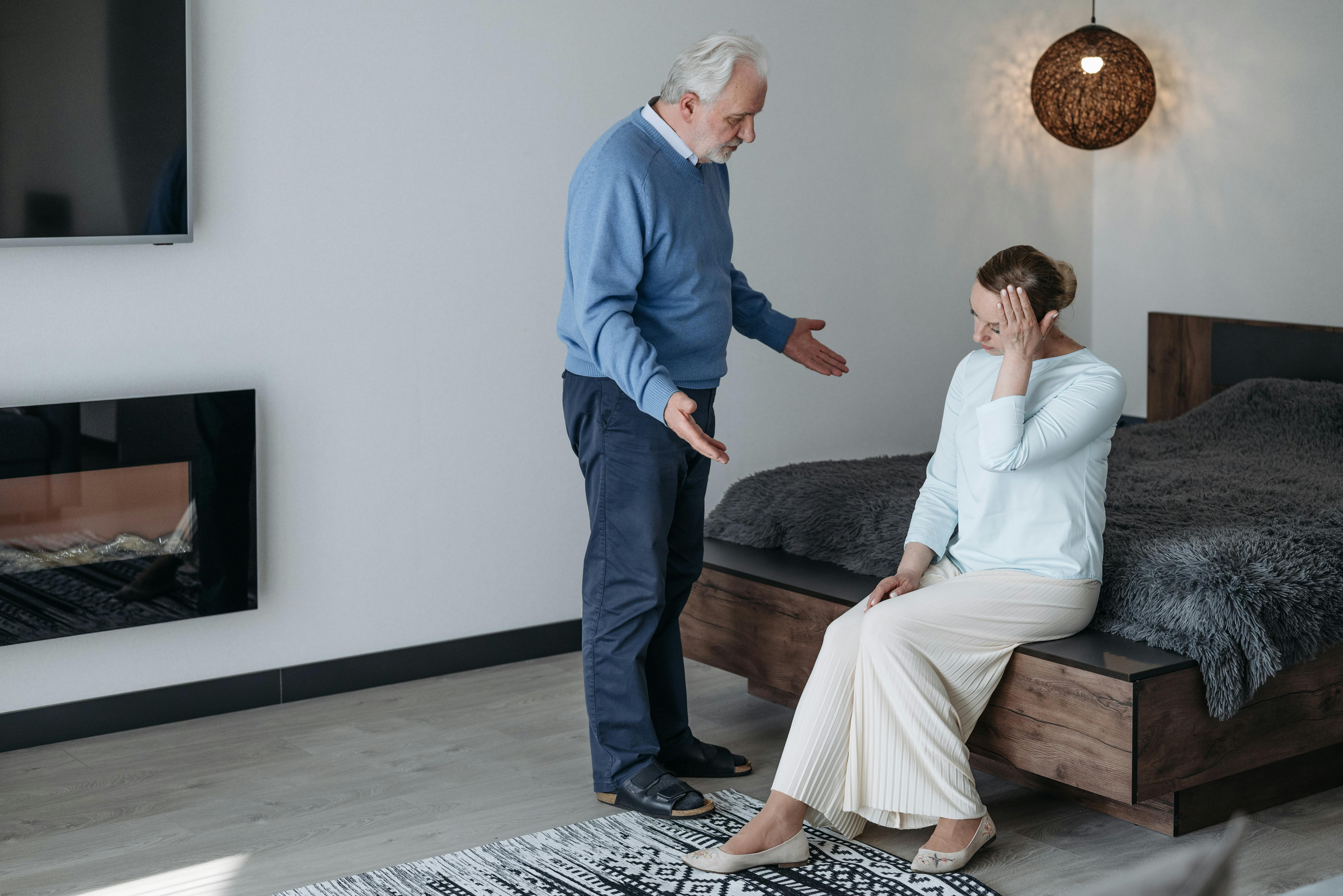 Elderly couple having a heartfelt conversation in a bedroom, signifying emotional intimacy.
